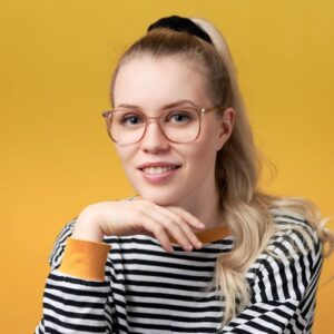 Hymyilevä kapea kasvoinen nainen, jolla pyöreäsankaiset ja isolinssiset vaalean ruskeat silmälasit. Lauralla on vaaleat pitkät hiukset, jotka ovat ponihännällä. Päällään Lauralla on mustavalkovaakaraitainen pitkähihainen pusero. Puseron hihansuut ovat oranssit.