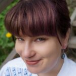 Naisoletettu henkilö, jolla tummat hiukset. Linda hymyilee ja hänellä on yllään sinivalkoinen pusero