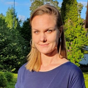 Naishenkilö, jolla on hyvmyilevät kasvot, vaaleat pitkät hiukset ja sininen pusero