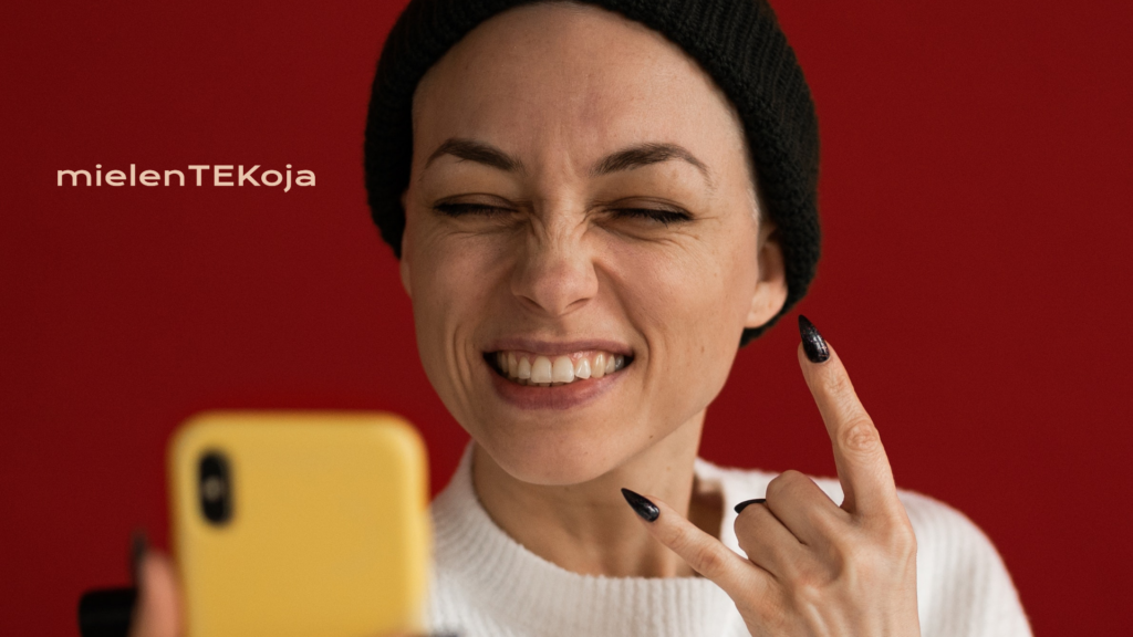 naisoletettu henkilö pipo päässä irvistää kameralle ja näyttää rock on- käsimerkkiä