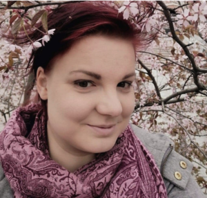 Sonja Sievers on hymyilevä punertava hiuksinen naisoletettu. Hänellä on tummat silmät. Kaulassaan Sonjalla on huivi, jossa on vaalean ja tumman lilan värisiä kuvioita. Sonjalla on taustalaan kukkiva puu.