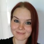 Punatukkainen hymyilevä naisoletettu, jolla on päällään musta pusero