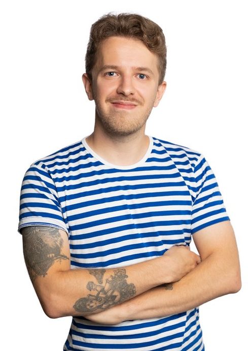 A brown-haired smiling man with a moustache. Henri is wearing a t-shirt with blue and white stripes.