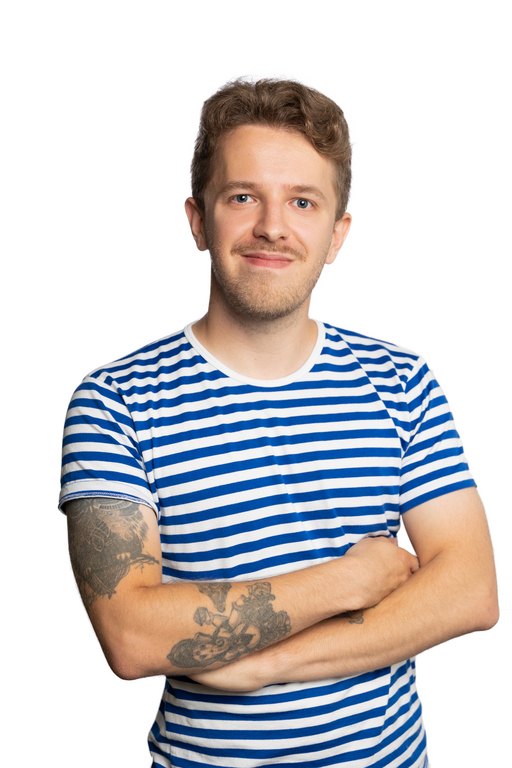 A brown-haired smiling man with a moustache. Henri is wearing a t-shirt with blue and white stripes.