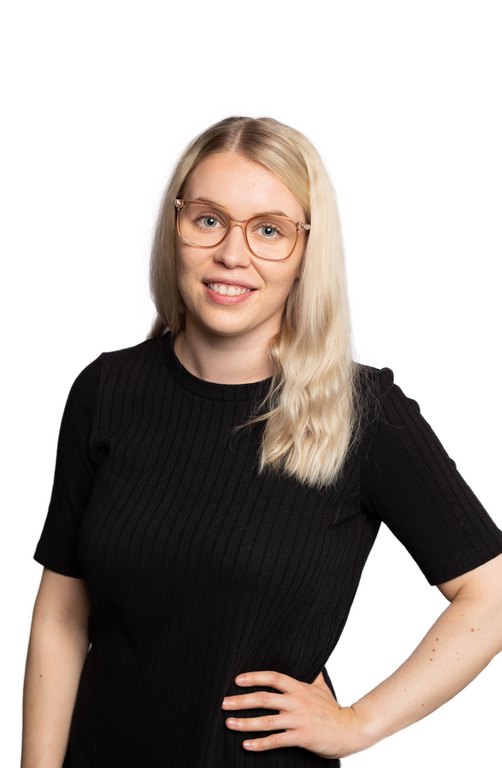A female presumed person with a blond long hair and light-skinned glasses. The person smiles and she wears a black shirt. 